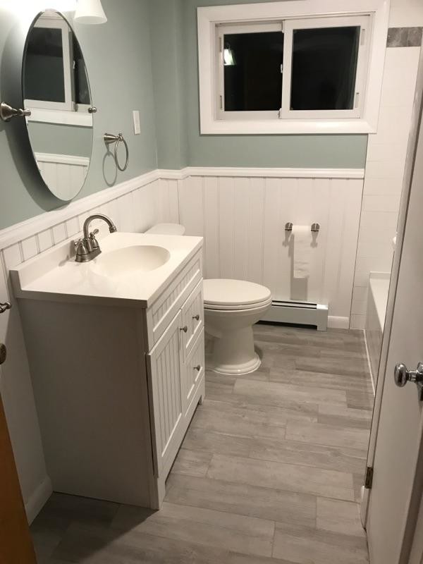 This is an example of a small traditional bathroom in Providence with shaker cabinets, white cabinets, a shower/bathtub combo, a one-piece toilet, white tile, porcelain tile, grey walls, porcelain floors, quartzite benchtops, beige floor and a shower curtain.