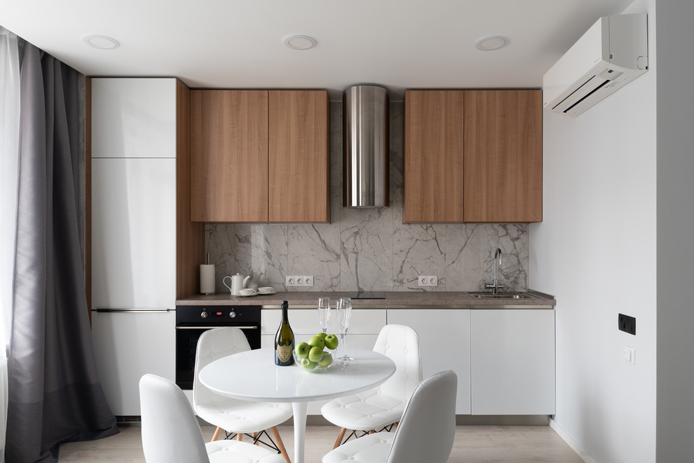 Inspiration for a contemporary single-wall eat-in kitchen in Saint Petersburg with flat-panel cabinets, light wood cabinets, grey splashback, marble splashback, black appliances, grey benchtop, a drop-in sink and no island.