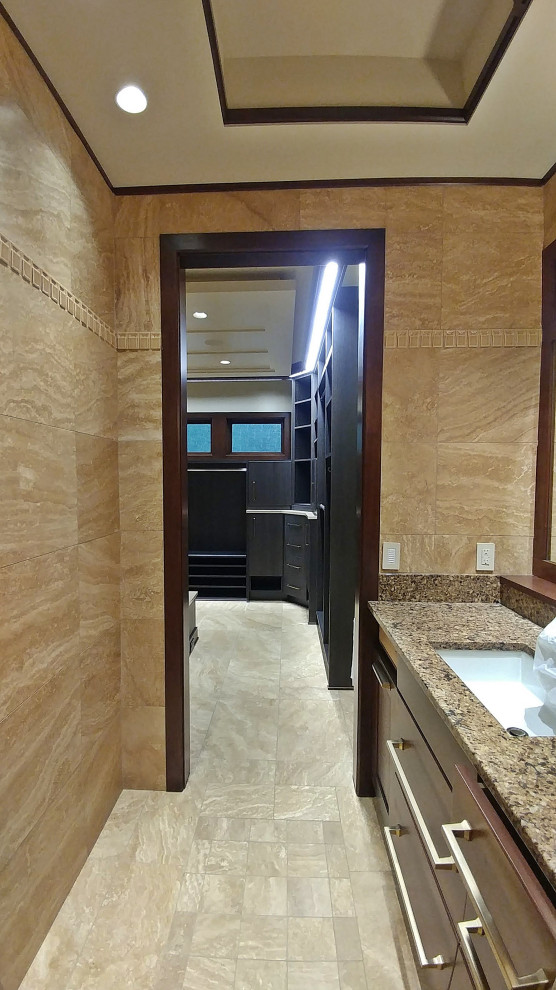 This is an example of a master bathroom in Kansas City with dark wood cabinets, a curbless shower, beige tile, beige walls, travertine floors, an undermount sink, beige floor, a hinged shower door, a double vanity, a built-in vanity and coffered.