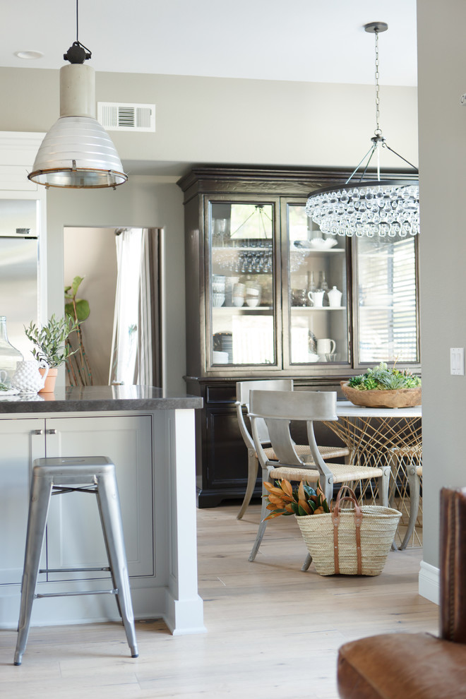 Large transitional l-shaped light wood floor open concept kitchen photo in Orange County with a farmhouse sink, beaded inset cabinets, white cabinets, beige backsplash, stone tile backsplash, stainless steel appliances, gray walls and an island