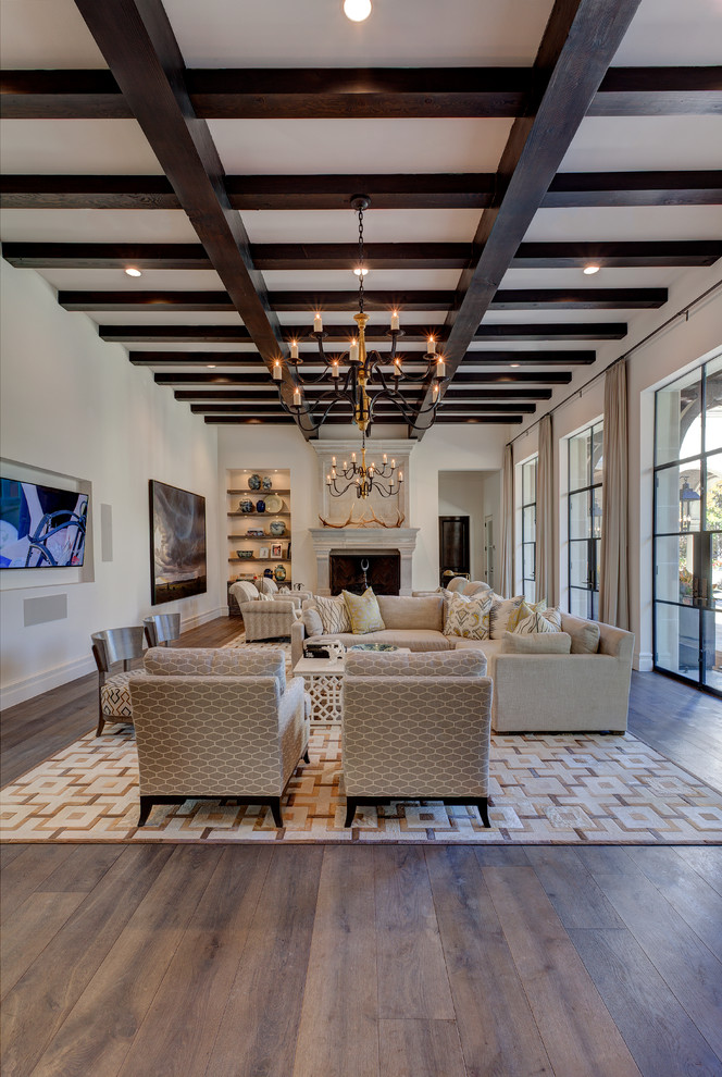 Inspiration for a large mediterranean open concept family room in Dallas with white walls, dark hardwood floors, no fireplace, a wall-mounted tv and brown floor.