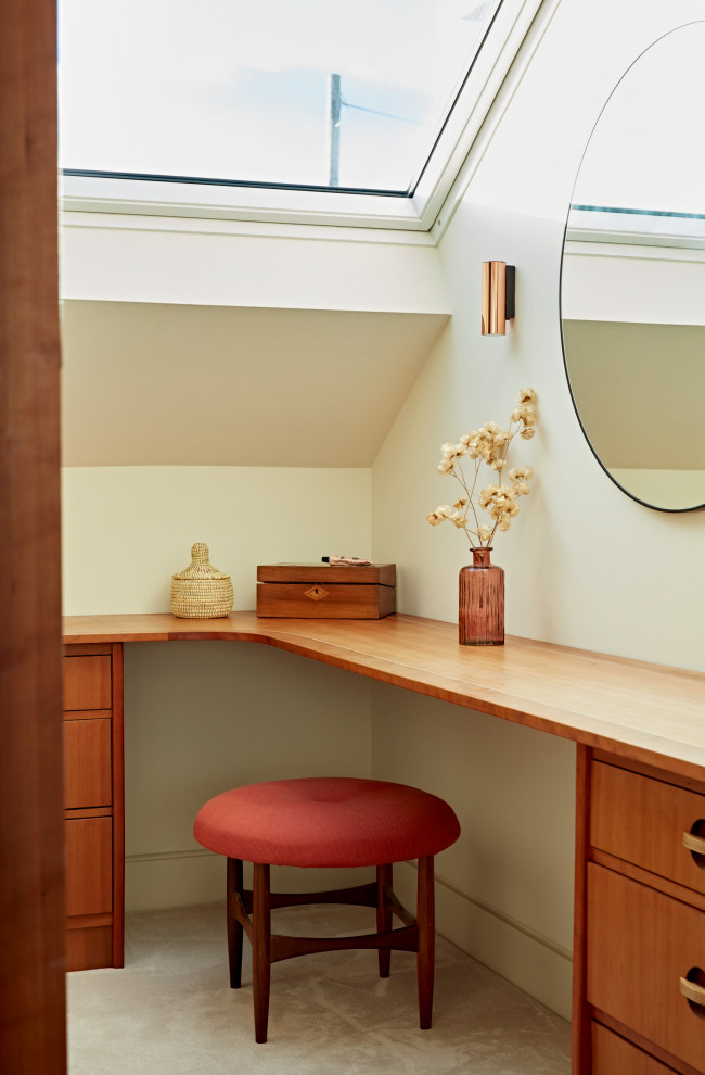 Immagine di un piccolo spazio per vestirsi unisex moderno con ante lisce, ante in legno scuro, moquette, pavimento beige e soffitto a volta
