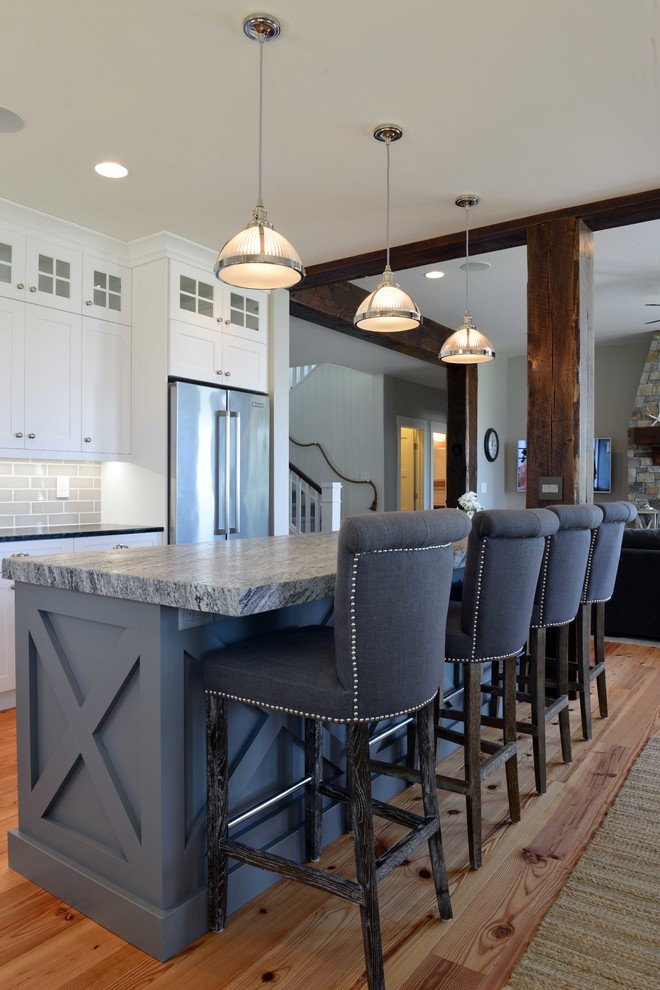 Eat-in kitchen - mid-sized transitional l-shaped light wood floor eat-in kitchen idea with shaker cabinets, white cabinets, granite countertops, gray backsplash, subway tile backsplash, stainless steel appliances, an island and an undermount sink