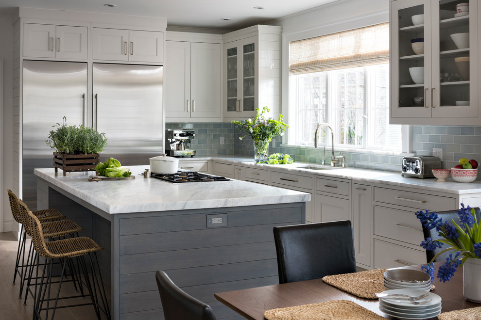 Photo of a transitional l-shaped eat-in kitchen in New York with an undermount sink, white cabinets, blue splashback, subway tile splashback, stainless steel appliances, with island and recessed-panel cabinets.
