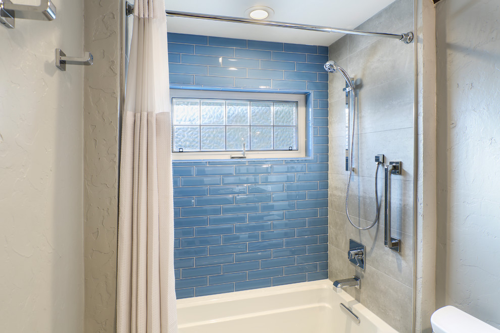 Inspiration for a mid-sized contemporary 3/4 bathroom in Other with raised-panel cabinets, dark wood cabinets, an alcove tub, a shower/bathtub combo, a two-piece toilet, blue tile, glass tile, beige walls, ceramic floors, an undermount sink, granite benchtops, beige floor and a shower curtain.