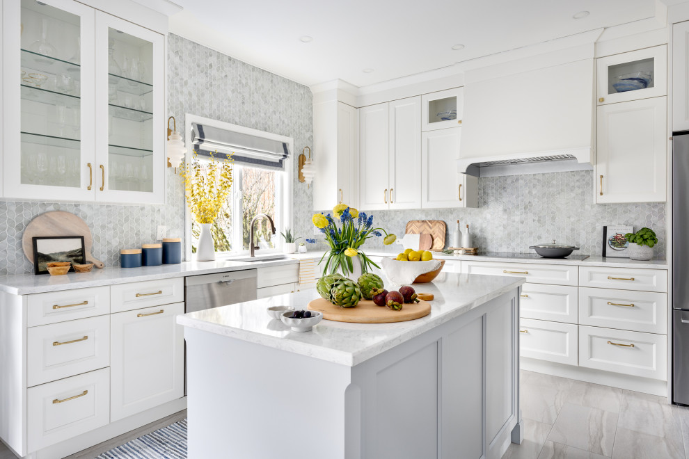 Inredning av ett klassiskt stort vit vitt kök, med en undermonterad diskho, luckor med infälld panel, vita skåp, bänkskiva i kvarts, grått stänkskydd, stänkskydd i glaskakel, rostfria vitvaror, klinkergolv i porslin, en köksö och grått golv