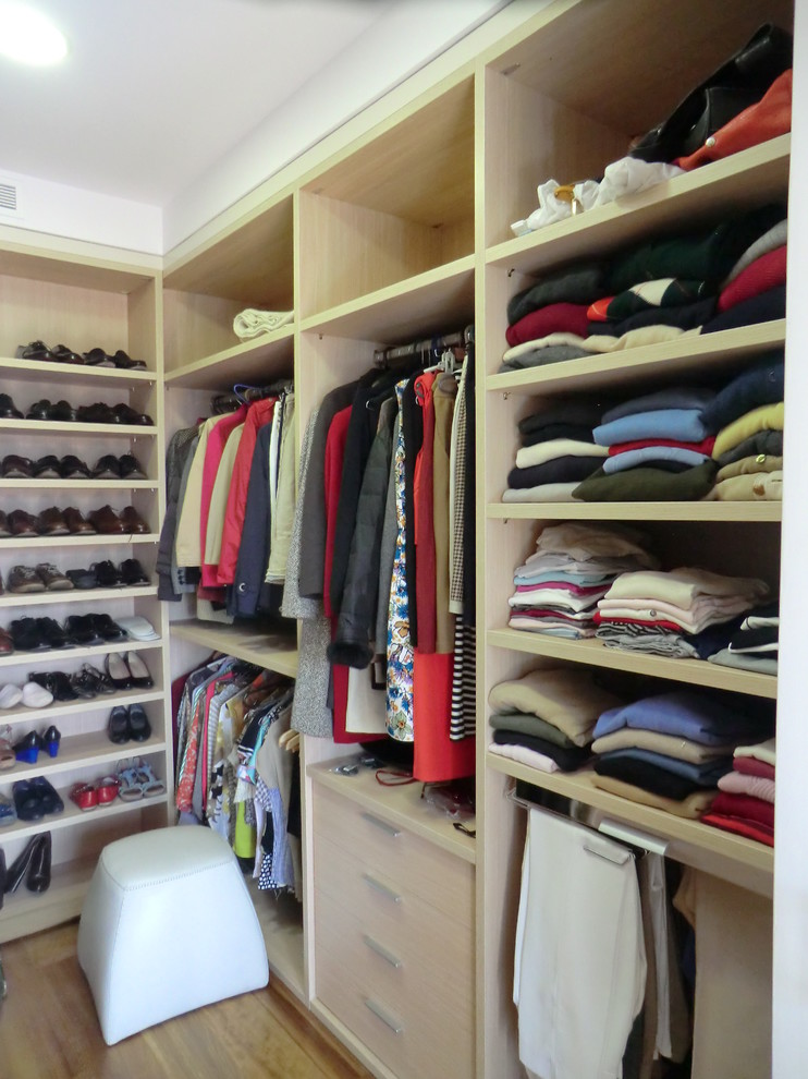 This is an example of a mid-sized traditional gender-neutral walk-in wardrobe in Madrid with open cabinets, light wood cabinets and medium hardwood floors.