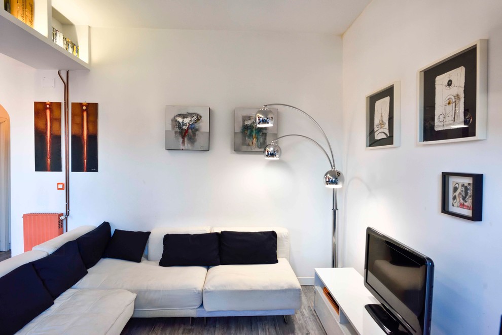 This is an example of a mid-sized contemporary open concept living room in Rome with white walls, laminate floors, a freestanding tv and grey floor.