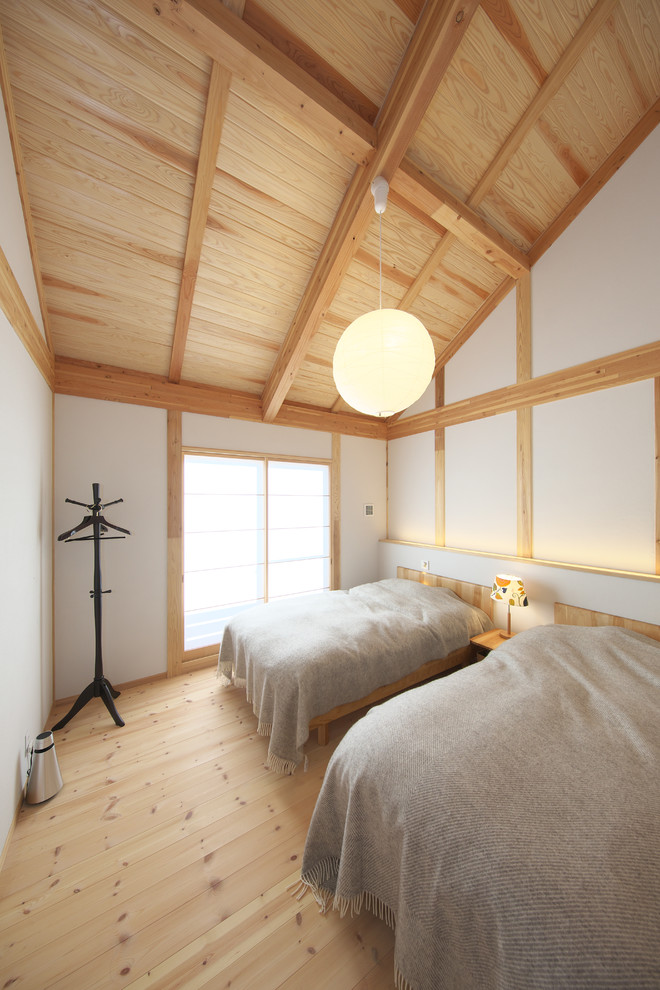 This is an example of an asian bedroom in Other with white walls, medium hardwood floors and brown floor.
