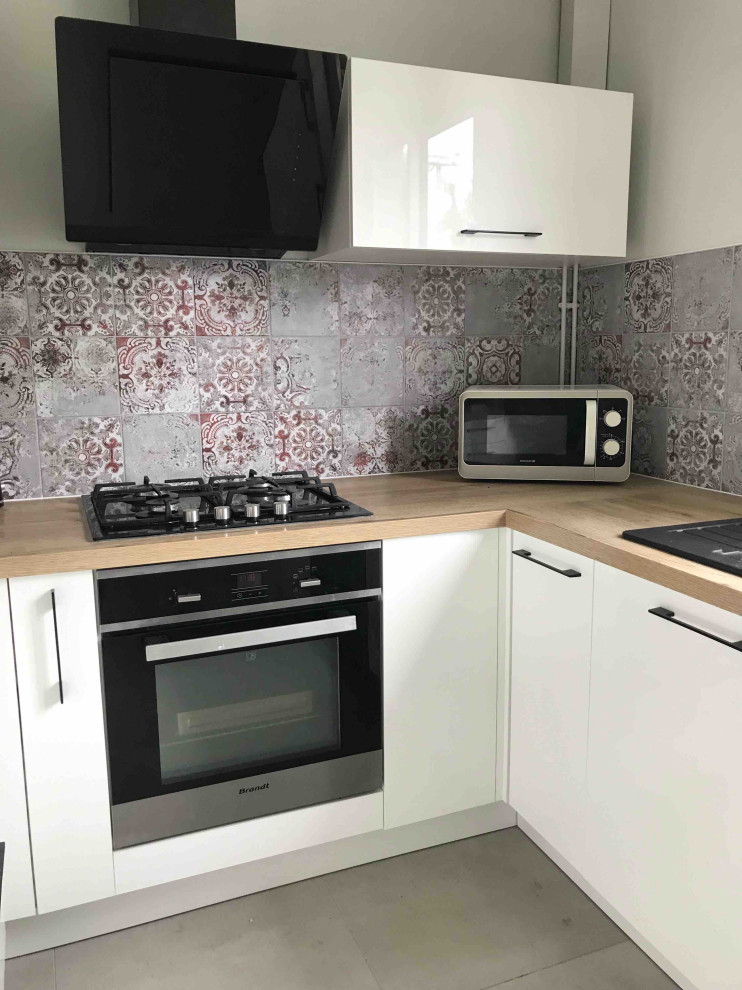 Exempel på ett litet modernt beige beige kök, med en dubbel diskho, luckor med profilerade fronter, vita skåp, laminatbänkskiva, rött stänkskydd, stänkskydd i cementkakel, svarta vitvaror, cementgolv och grått golv