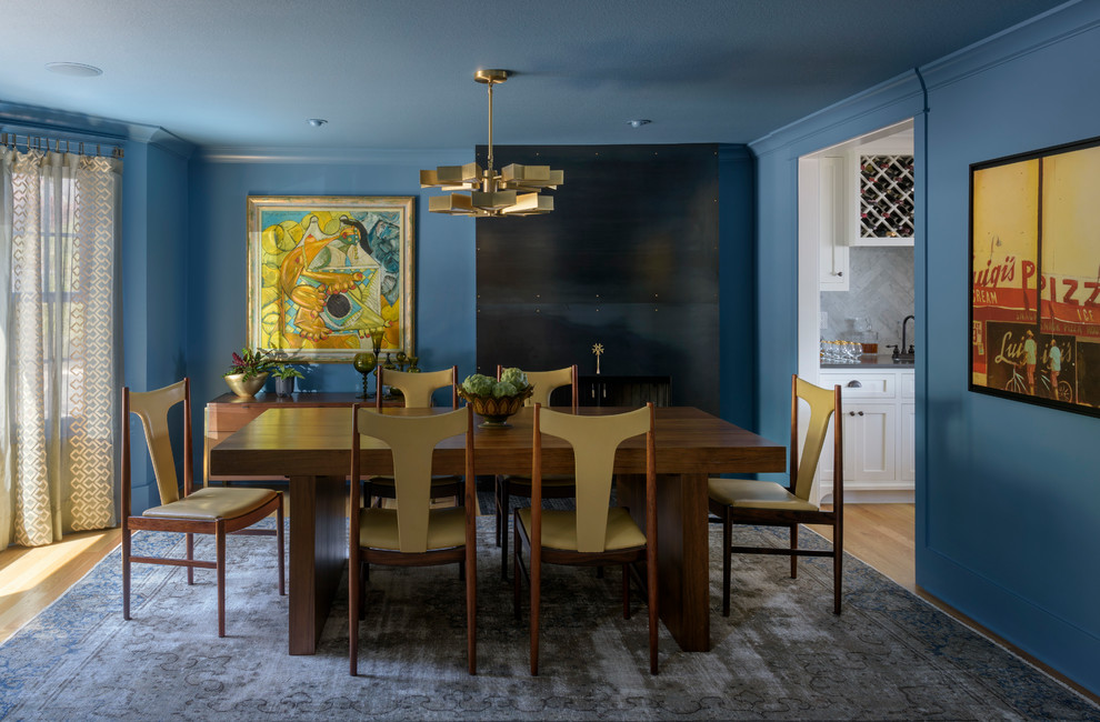 Mid-sized transitional separate dining room in Portland with blue walls, a standard fireplace, a metal fireplace surround, light hardwood floors and brown floor.