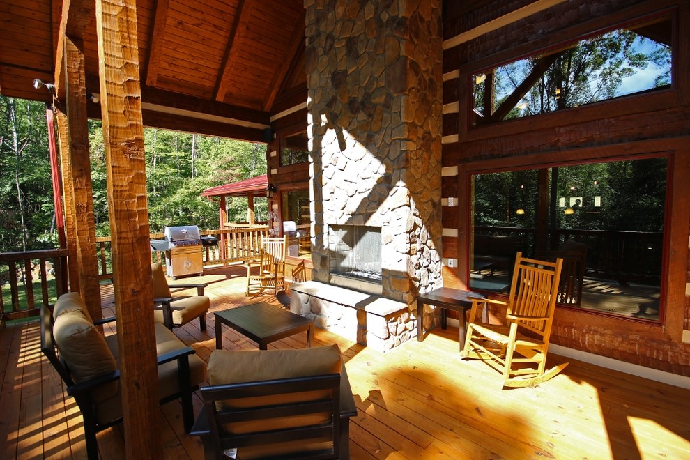 Large mountain style backyard deck photo in Columbus with a fire pit and a roof extension