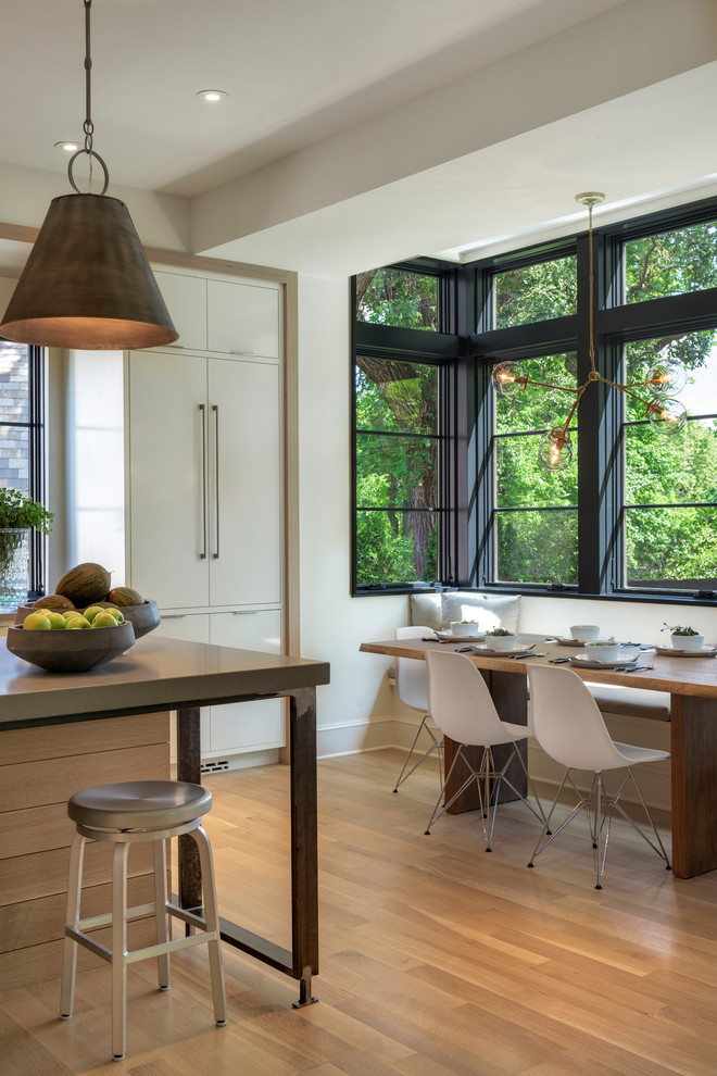 Large transitional l-shaped light wood floor open concept kitchen photo in Minneapolis with an undermount sink, flat-panel cabinets, white cabinets, solid surface countertops, white backsplash, stone slab backsplash, paneled appliances and an island
