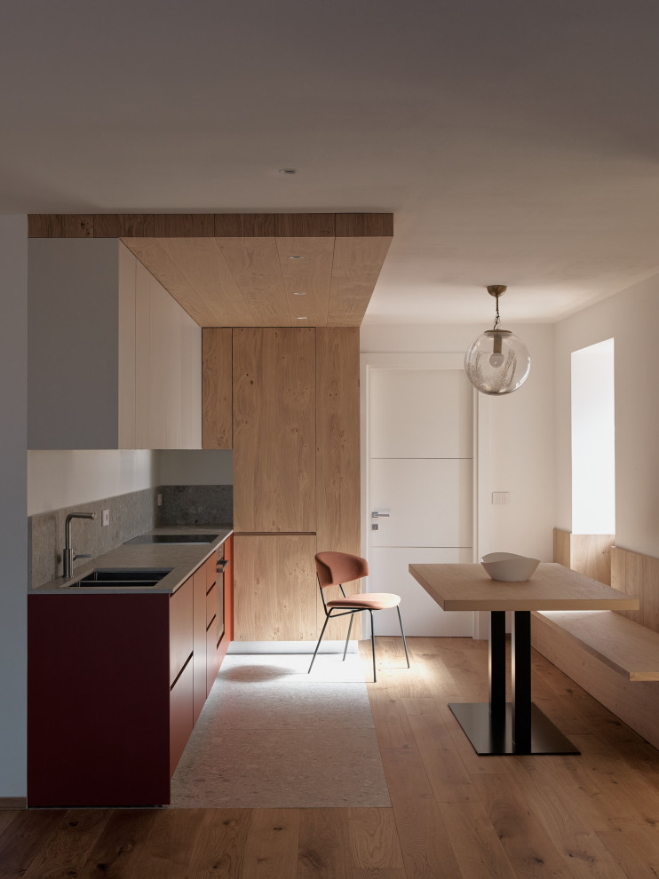 На фото: маленькая угловая кухня в стиле модернизм с обеденным столом, плоскими фасадами, красными фасадами и серой столешницей без острова для на участке и в саду