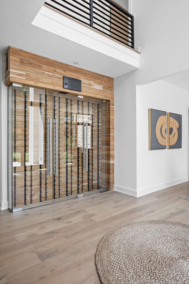 Imagen de distribuidor minimalista extra grande con paredes blancas, suelo de madera clara, puerta doble, puerta negra, suelo multicolor y panelado
