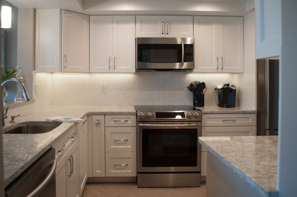 Example of a mid-sized transitional u-shaped eat-in kitchen design with an undermount sink, shaker cabinets, white cabinets, quartz countertops, white backsplash, marble backsplash, stainless steel appliances and no island
