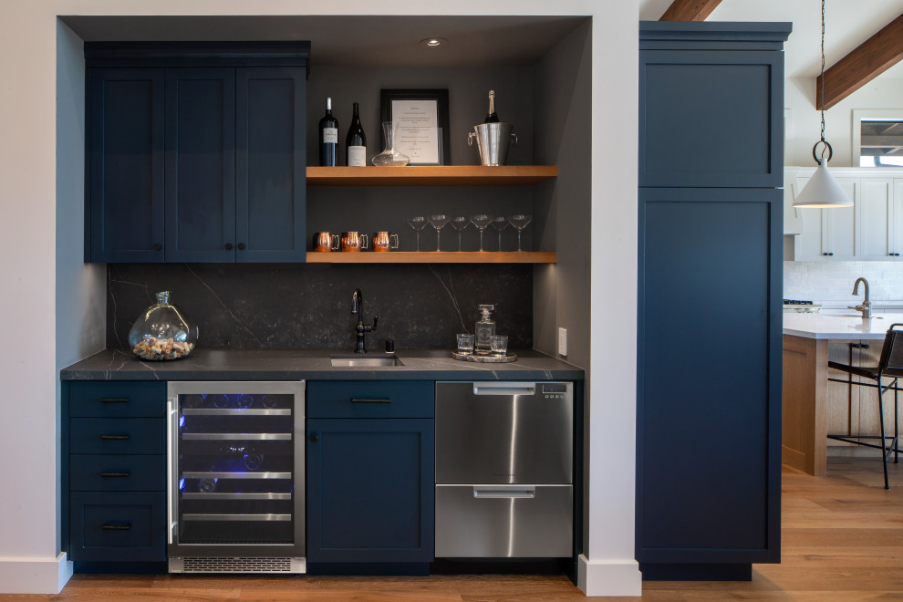 Inspiration for a large transitional single-wall wet bar in San Francisco with a drop-in sink, raised-panel cabinets, blue cabinets, granite benchtops, grey splashback, granite splashback, light hardwood floors, brown floor and grey benchtop.