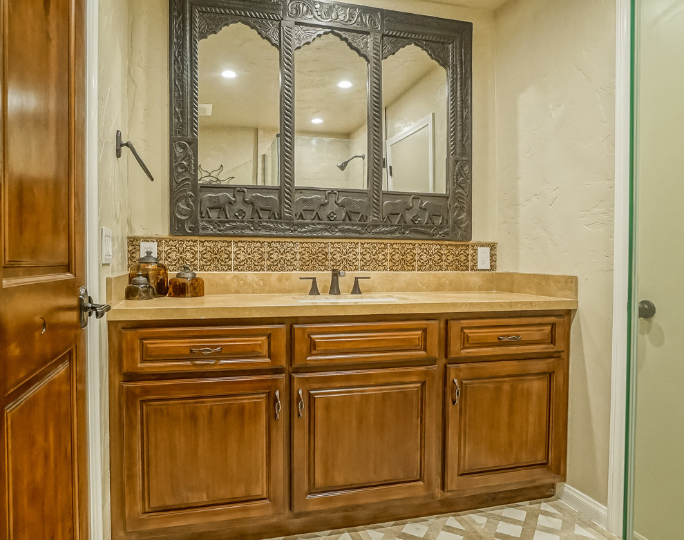 This is an example of a mid-sized traditional 3/4 bathroom in Los Angeles with raised-panel cabinets, dark wood cabinets, an alcove shower, a two-piece toilet, beige tile, white tile, porcelain tile, beige walls, cement tiles, an undermount sink, concrete benchtops, multi-coloured floor and a hinged shower door.