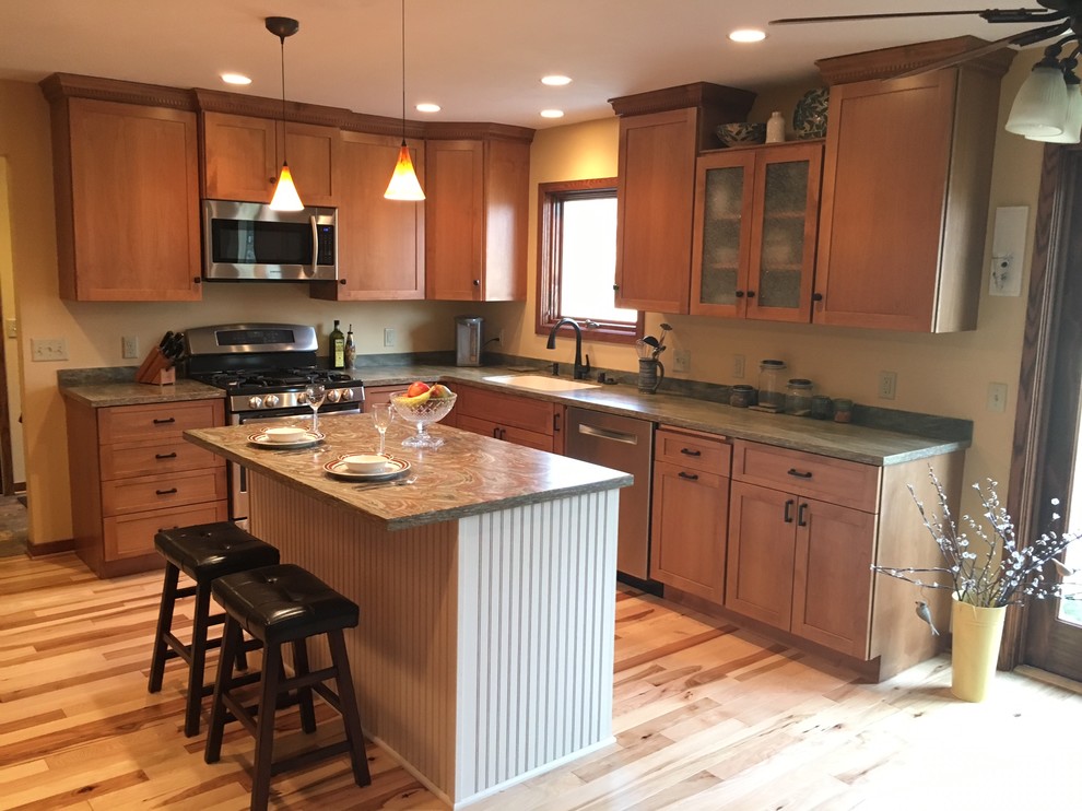 Eat-in kitchen - mid-sized transitional l-shaped light wood floor and brown floor eat-in kitchen idea in Milwaukee with an integrated sink, recessed-panel cabinets, medium tone wood cabinets, solid surface countertops, stainless steel appliances and an island