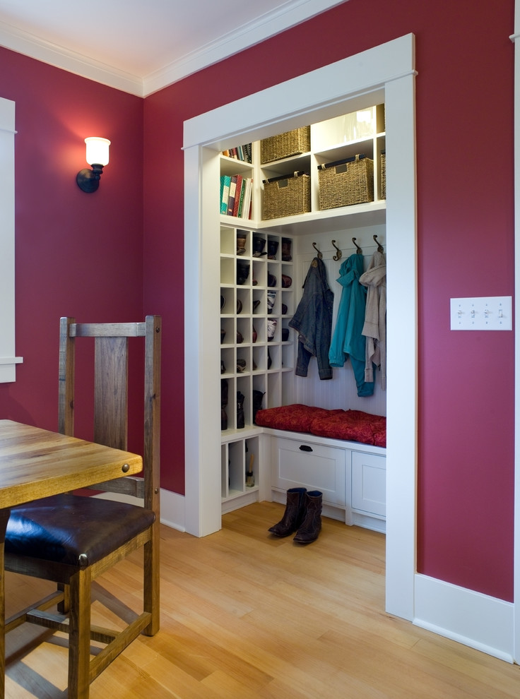 Photo of a mid-sized traditional gender-neutral built-in wardrobe in Seattle with recessed-panel cabinets, white cabinets and light hardwood floors.