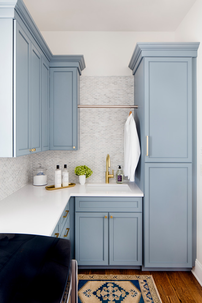 Design ideas for a mid-sized traditional l-shaped dedicated laundry room in Baltimore with an undermount sink, recessed-panel cabinets, blue cabinets, white walls, medium hardwood floors, a side-by-side washer and dryer and brown floor.