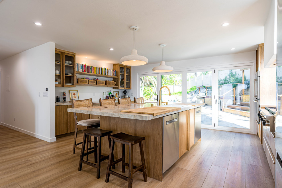This is an example of a contemporary galley kitchen/diner in Orange County with a built-in sink, flat-panel cabinets, brown cabinets, marble worktops, beige splashback, marble splashback, coloured appliances, light hardwood flooring, an island, brown floors, grey worktops and exposed beams.