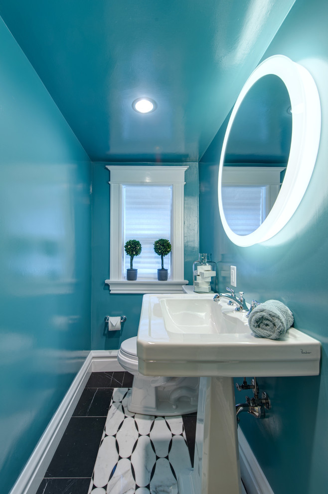 This is an example of a small contemporary powder room in St Louis with a one-piece toilet, blue walls, a pedestal sink, black floor and marble floors.