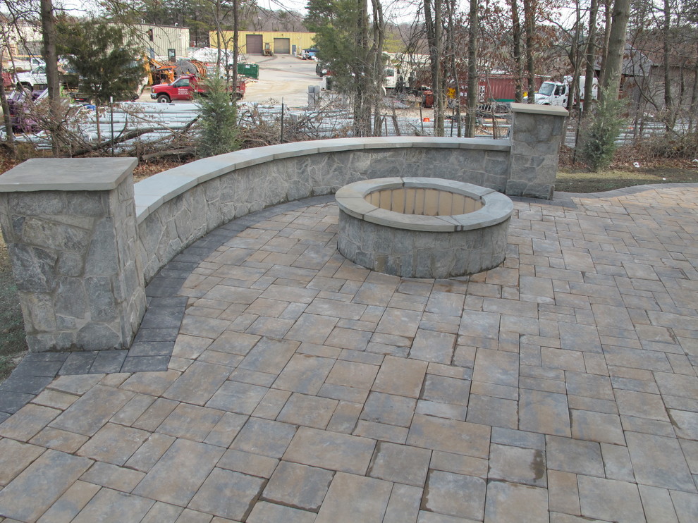 This is an example of a mid-sized traditional backyard patio in Baltimore with a fire feature, natural stone pavers and no cover.