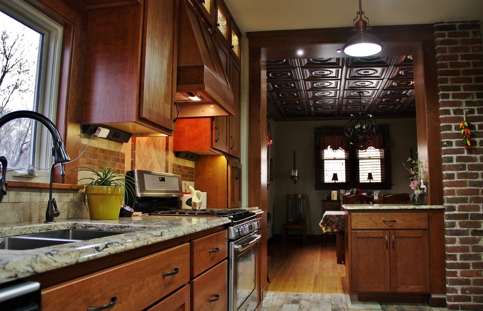 Example of a mid-sized transitional galley ceramic tile enclosed kitchen design with an undermount sink, shaker cabinets, medium tone wood cabinets, quartz countertops, beige backsplash, stone tile backsplash, stainless steel appliances and a peninsula