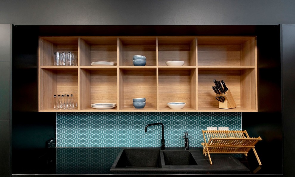 Design ideas for a mid-sized modern single-wall eat-in kitchen in Newcastle - Maitland with a double-bowl sink, flat-panel cabinets, black cabinets, laminate benchtops, blue splashback, ceramic splashback, black appliances, dark hardwood floors, with island and black benchtop.