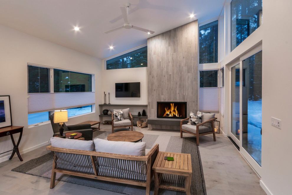 This is an example of a contemporary open concept living room in Sacramento with white walls, porcelain floors, a standard fireplace, a wood fireplace surround, a wall-mounted tv and beige floor.