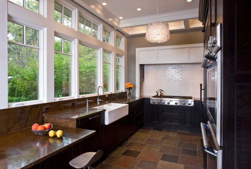 Inspiration for a transitional u-shaped open concept kitchen remodel in Chicago with a farmhouse sink, recessed-panel cabinets, dark wood cabinets, granite countertops, brown backsplash, glass tile backsplash and paneled appliances
