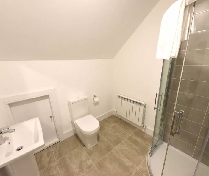 Exempel på ett mellanstort modernt en-suite badrum, med ett hörnbadkar, en kantlös dusch, en vägghängd toalettstol, beige kakel, keramikplattor, beige väggar, klinkergolv i porslin, ett nedsänkt handfat och beiget golv