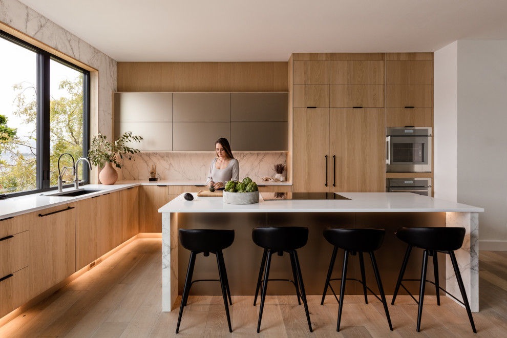This is an example of a mid-sized contemporary l-shaped kitchen in Seattle with flat-panel cabinets and light wood cabinets.