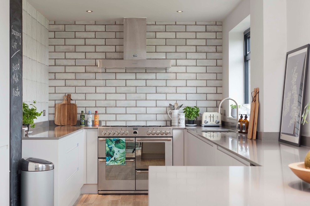 Inspiration for a small contemporary u-shaped kitchen in Essex with an undermount sink, flat-panel cabinets, white cabinets, white splashback, subway tile splashback, medium hardwood floors, a peninsula and brown floor.