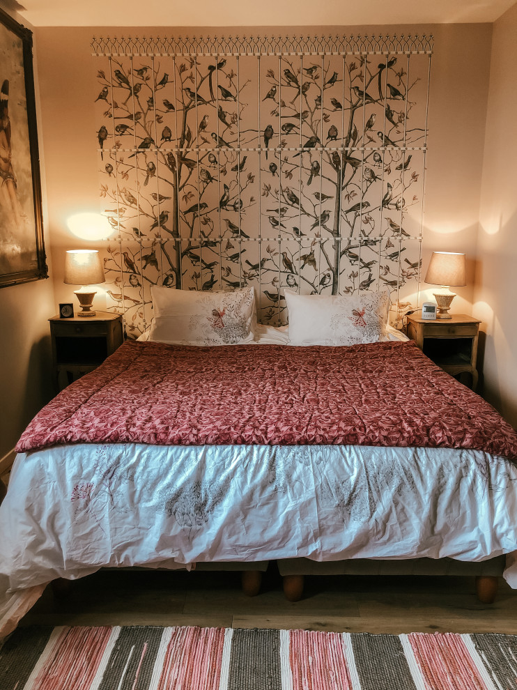 Photo of a mid-sized traditional master bedroom in Paris with pink walls and light hardwood floors.