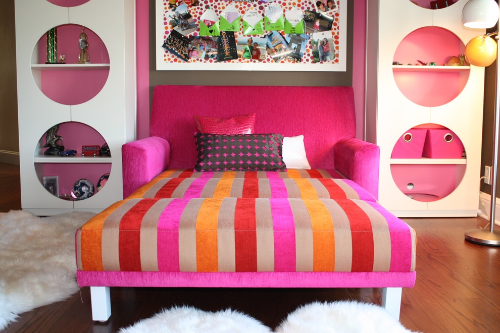 Photo of an eclectic kids' room for girls in Orange County with pink walls and medium hardwood floors.