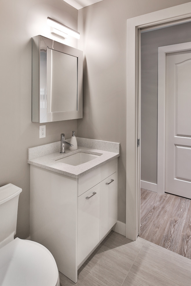 This is an example of a small contemporary 3/4 bathroom in Other with white cabinets, white benchtops, a one-piece toilet, grey walls, porcelain floors, an undermount sink, an alcove shower, a hinged shower door, flat-panel cabinets, white tile, porcelain tile and beige floor.