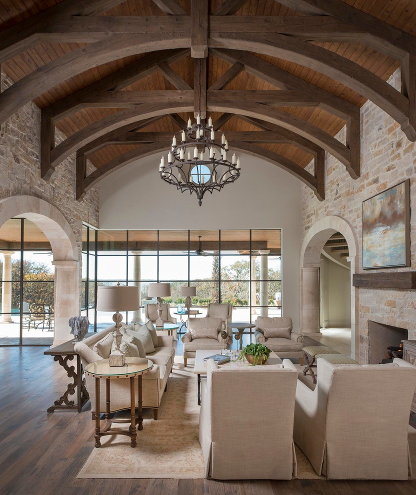 Expansive mediterranean open concept family room in Dallas with beige walls, light hardwood floors, a standard fireplace, a stone fireplace surround and a wall-mounted tv.