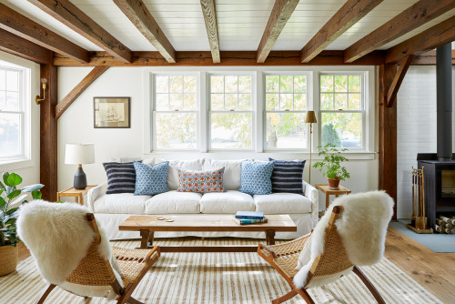 A bright living room with white furniture and wooden beams, complemented by light colours.