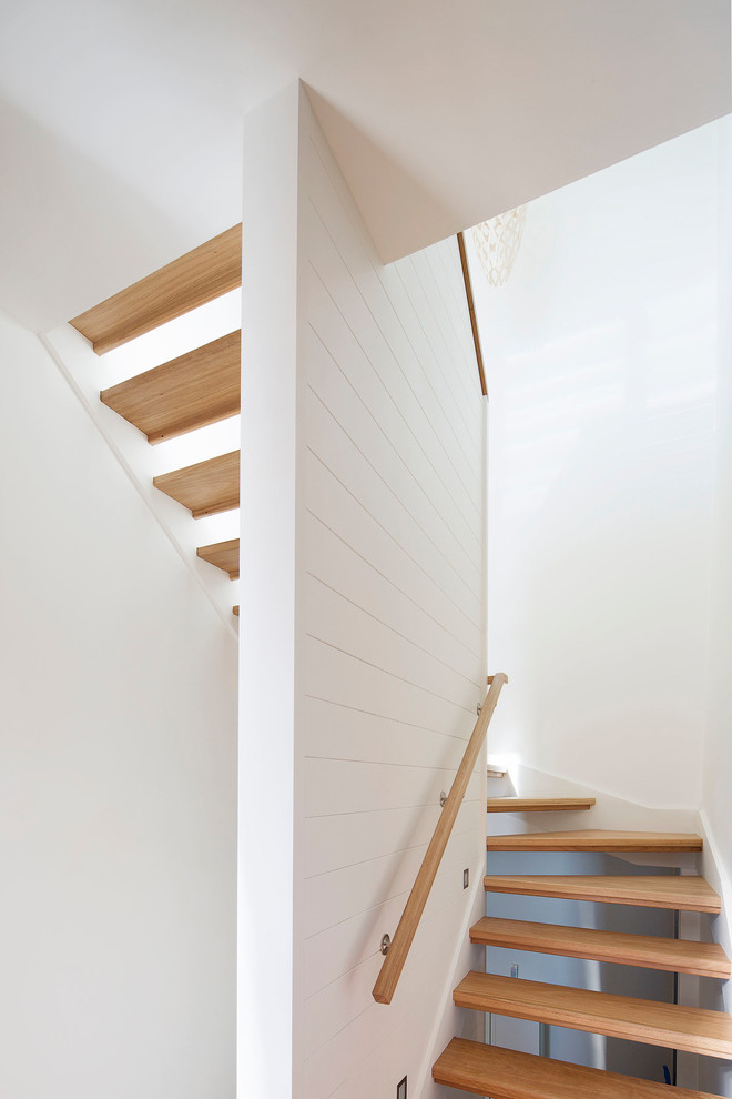This is an example of a mid-sized beach style wood u-shaped staircase in Sydney with open risers and wood railing.