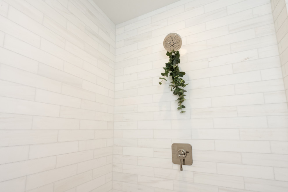 Идея дизайна: большая главная ванная комната в классическом стиле с фасадами островного типа, белыми фасадами, накладной ванной, душем в нише, унитазом-моноблоком, белой плиткой, мраморной плиткой, белыми стенами, полом из терраццо, врезной раковиной, мраморной столешницей, белым полом, душем с распашными дверями, серой столешницей, сиденьем для душа, тумбой под одну раковину и встроенной тумбой