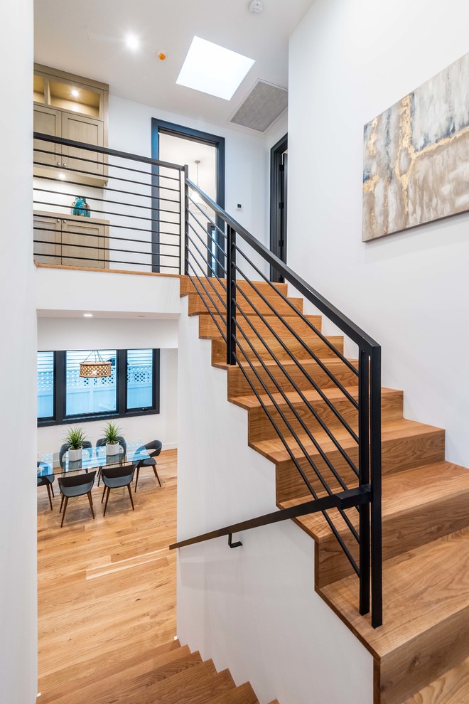 Mid-sized beach style wood u-shaped staircase in Los Angeles with wood risers and metal railing.