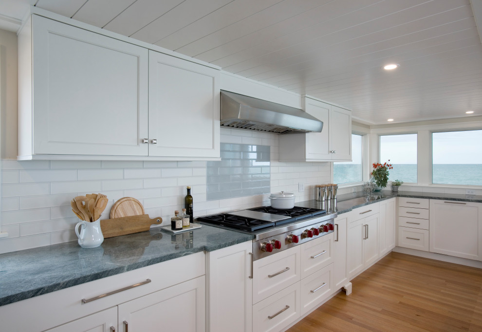 Design ideas for an expansive beach style u-shaped eat-in kitchen in Boston with an undermount sink, recessed-panel cabinets, white cabinets, quartzite benchtops, multi-coloured splashback, cement tile splashback, panelled appliances, light hardwood floors, with island and green benchtop.