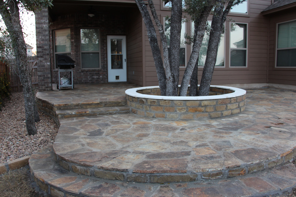 Design ideas for a mid-sized traditional partial sun backyard stone landscaping in Austin.