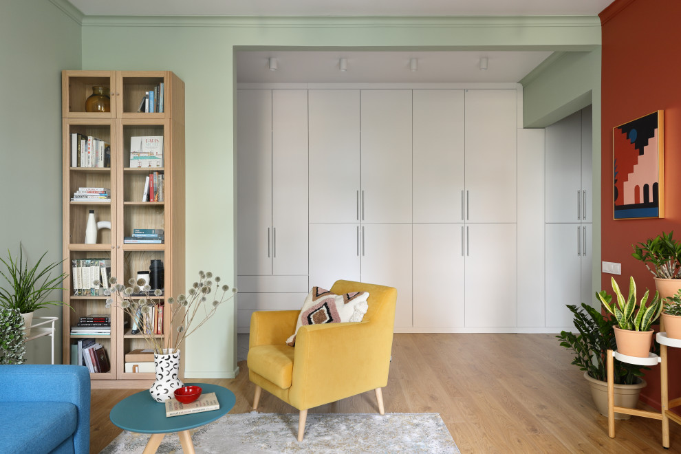 На фото: гостиная комната среднего размера в скандинавском стиле с разноцветными стенами, паркетным полом среднего тона, коричневым полом и синим диваном без телевизора