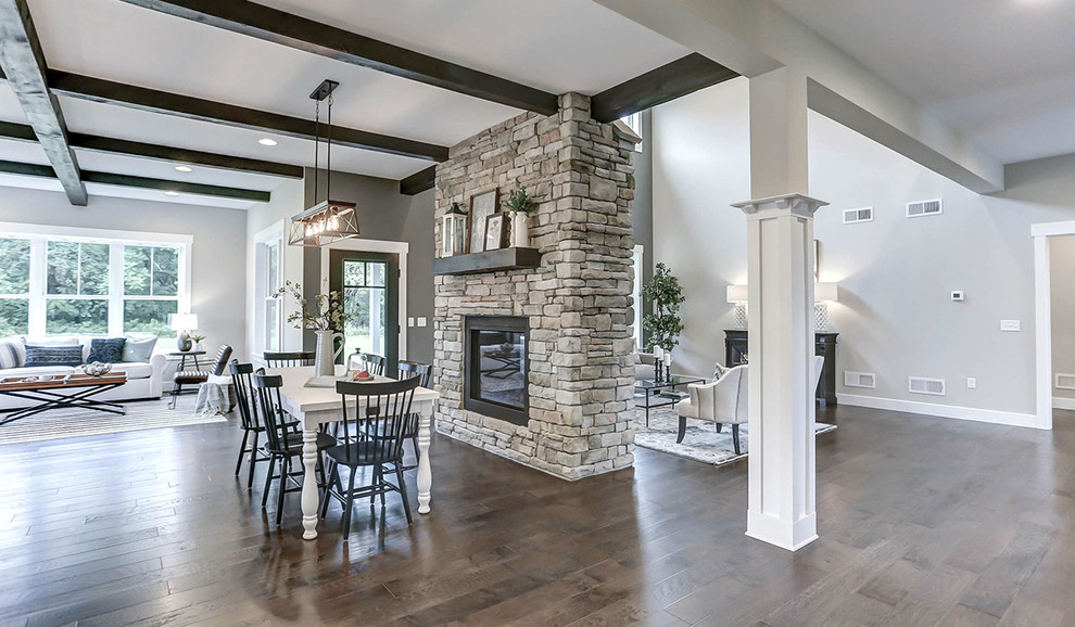Expansive country kitchen/dining combo in Other with grey walls, medium hardwood floors, a two-sided fireplace and a stone fireplace surround.