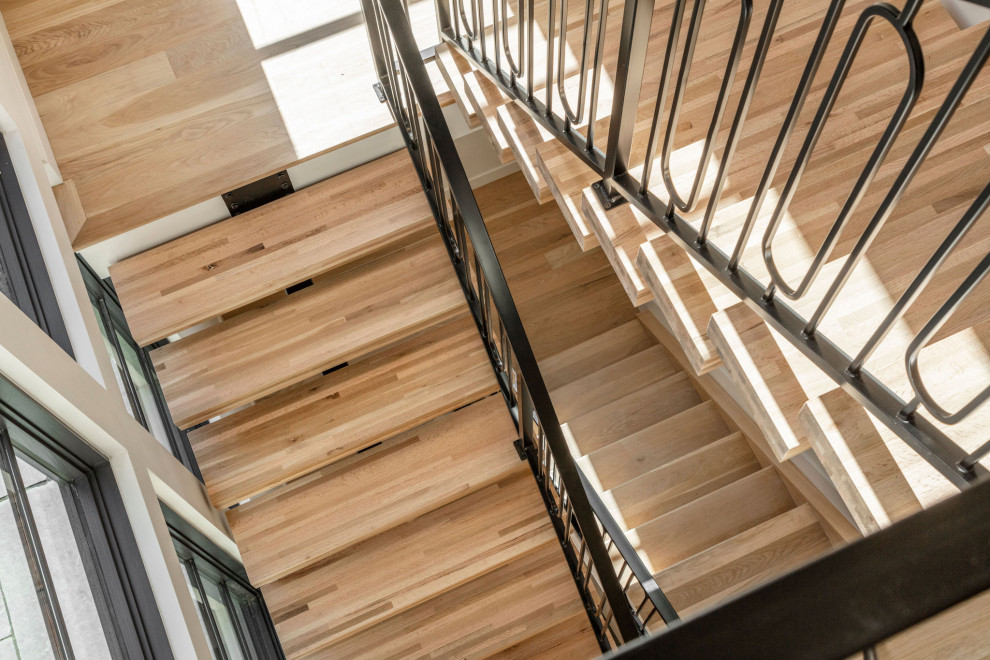 На фото: большая п-образная металлическая лестница в стиле модернизм с деревянными ступенями и металлическими перилами с