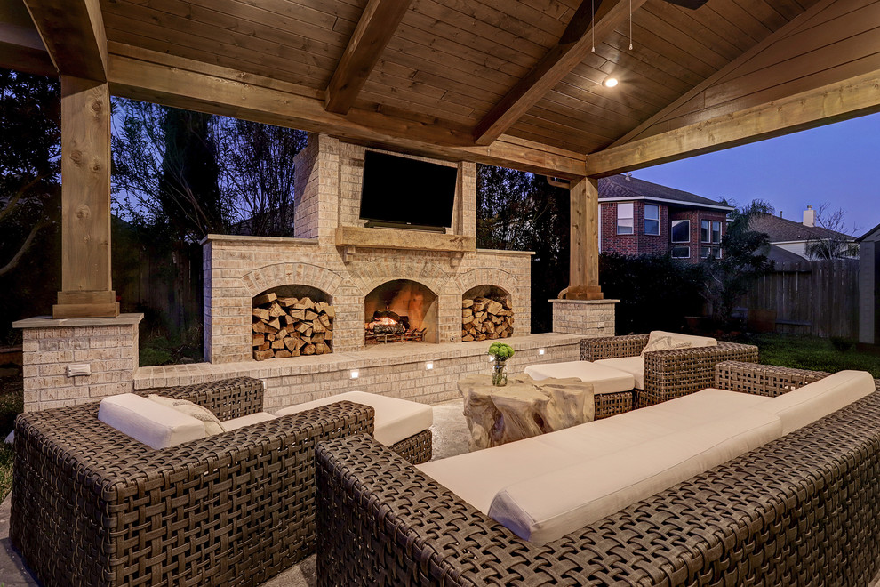 This is an example of a mid-sized traditional backyard patio in Houston with with fireplace, concrete slab and a roof extension.