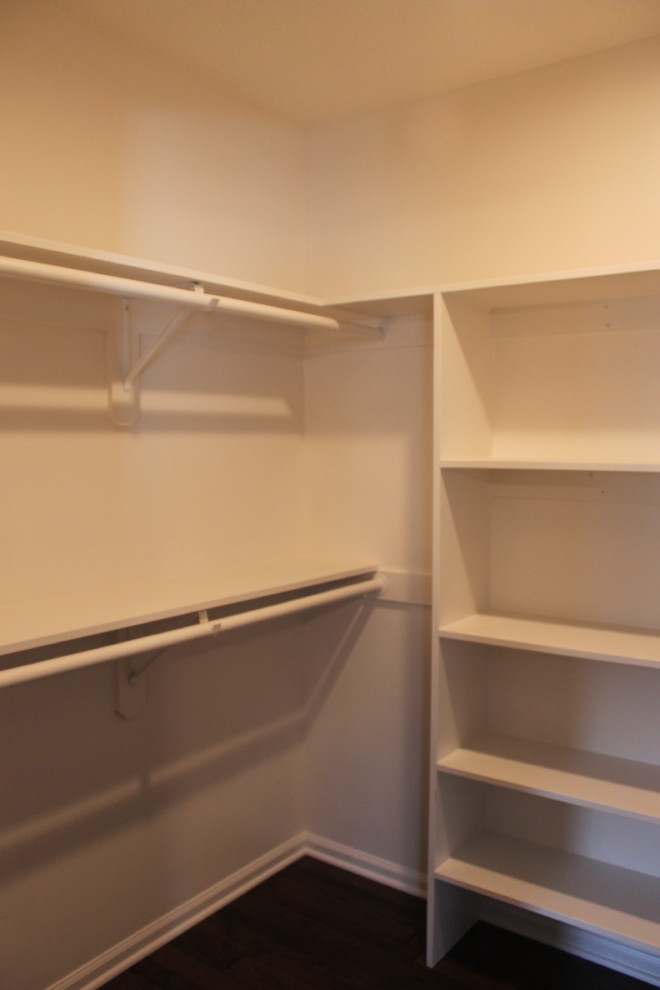 This is an example of a mid-sized transitional gender-neutral walk-in wardrobe in Kansas City with open cabinets, white cabinets and dark hardwood floors.